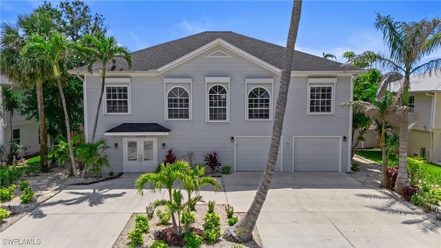 21075 Saint Peters Dr S, Fort Myers Beach, FL 33931 - view of front facade with concrete driveway, an attached garage, french doors, and roof with shingles