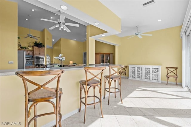 21075 Saint Peters Dr S, Fort Myers Beach, FL 33931 - kitchen with ceiling fan, recessed lighting, stainless steel microwave, a breakfast bar area, and light tile patterned flooring
