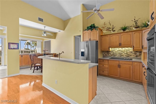 21075 Saint Peters Dr S, Fort Myers Beach, FL 33931 - kitchen with black appliances, a ceiling fan, decorative backsplash, a kitchen island with sink, and a high ceiling