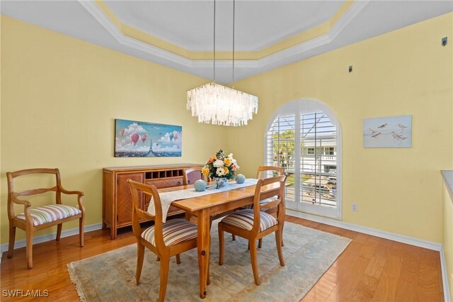 21075 Saint Peters Dr S, Fort Myers Beach, FL 33931 - dining space with a tray ceiling, light wood-style flooring, baseboards, a chandelier, and ornamental molding