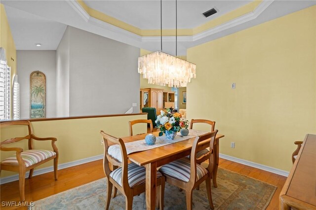 21075 Saint Peters Dr S, Fort Myers Beach, FL 33931 - dining space featuring wood finished floors, a chandelier, a raised ceiling, baseboards, and ornamental molding