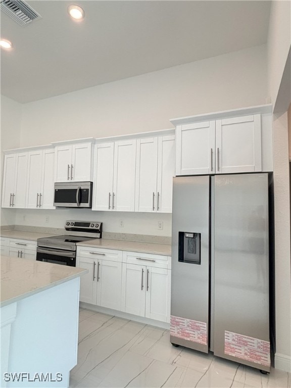 111 Monroe Ave, Lehigh Acres, FL 33936 - kitchen featuring appliances with stainless steel finishes, white cabinets, light stone countertops, light marble finish floors, and recessed lighting
