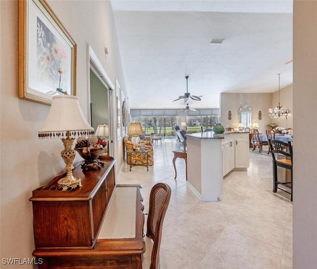 522 Countryside Dr, Naples, FL 34104 - kitchen featuring white cabinets, light tile patterned flooring, ceiling fan with notable chandelier, a breakfast bar, and a kitchen island