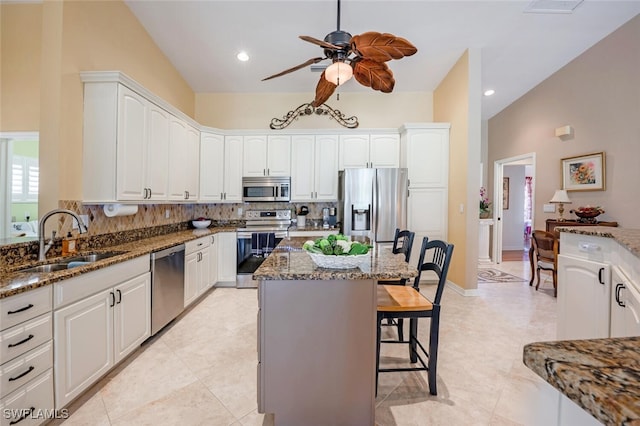 522 Countryside Dr, Naples, FL 34104 - kitchen with dark stone counters, a ceiling fan, a sink, a breakfast bar, and appliances with stainless steel finishes