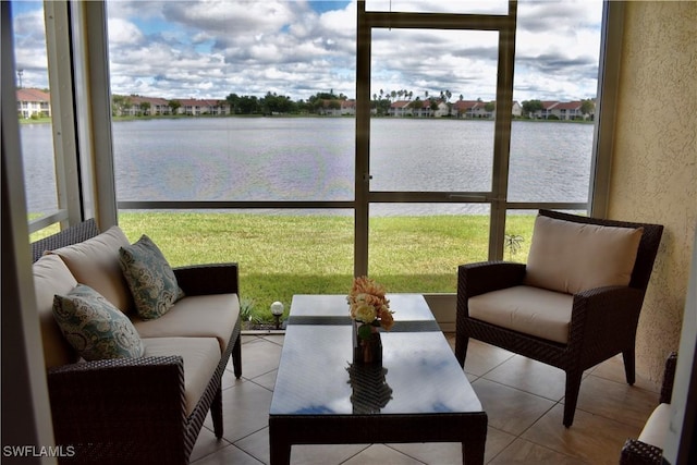 sunroom with a textured wall, a water view, and tile patterned floors
