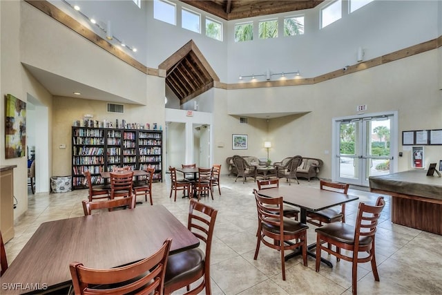 tiled dining space with a wealth of natural light, a towering ceiling, and french doors