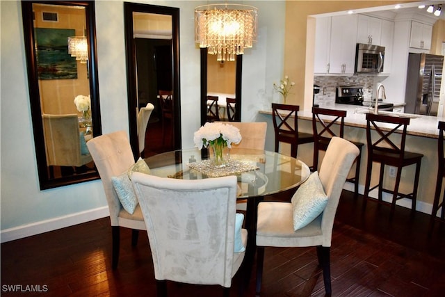 dining area featuring a notable chandelier, baseboards, and dark wood-type flooring