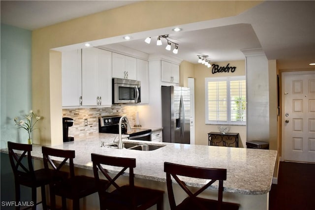 kitchen with a peninsula, light stone countertops, appliances with stainless steel finishes, and decorative backsplash