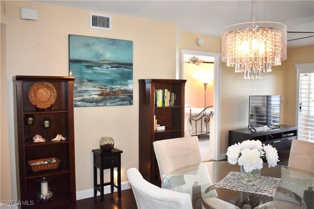 dining space with wood finished floors, visible vents, baseboards, and ceiling fan with notable chandelier