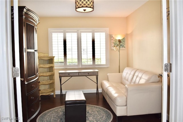 sitting room with dark wood-type flooring and baseboards