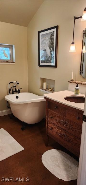 3105 Secretariat Dr, Labelle, FL 33935 - bathroom featuring a freestanding bath, vaulted ceiling, vanity, and baseboards