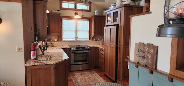 3105 Secretariat Dr, Labelle, FL 33935 - kitchen featuring light stone counters, a sink, stainless steel electric stove, light wood-style floors, and brown cabinetry
