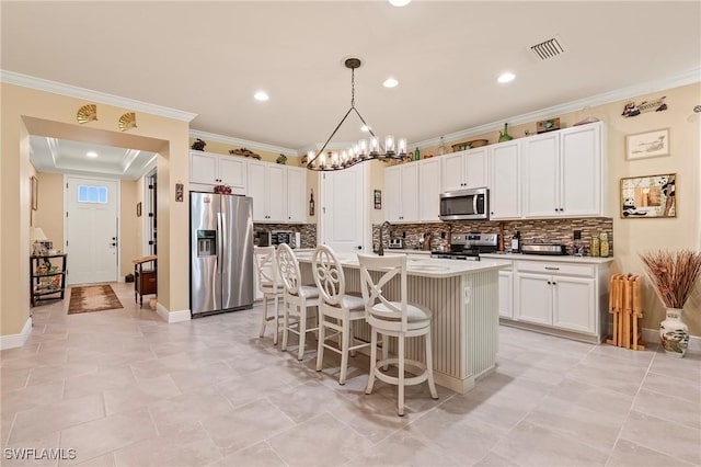 3865 Helmsman Dr, Naples, FL 34120 - kitchen with appliances with stainless steel finishes, decorative backsplash, an island with sink, a kitchen bar, and ornamental molding