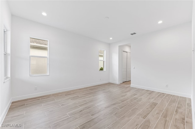 empty room with baseboards, recessed lighting, and light wood-style floors