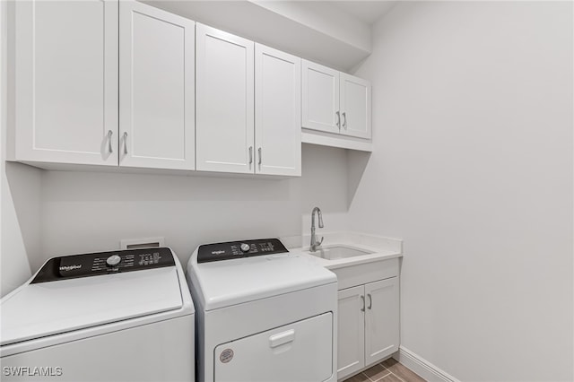 washroom with a sink, cabinet space, washer and clothes dryer, baseboards, and wood finished floors
