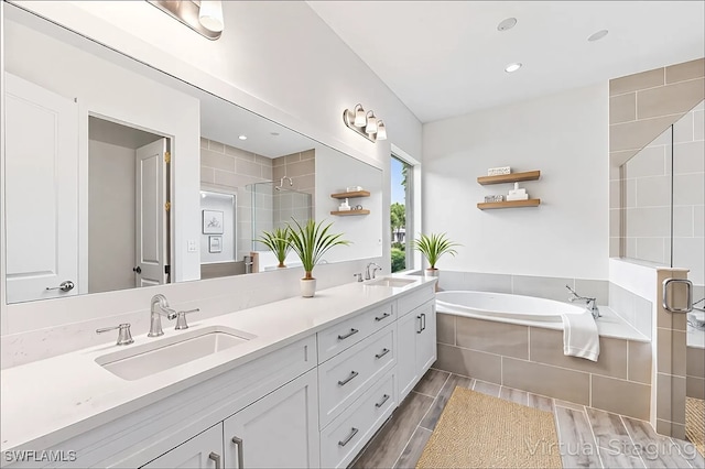full bathroom with a stall shower, a garden tub, double vanity, and a sink