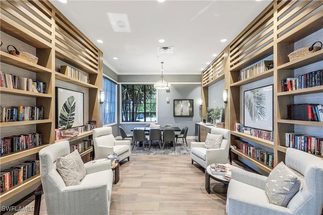 living area with ornamental molding, recessed lighting, visible vents, and light wood-style floors