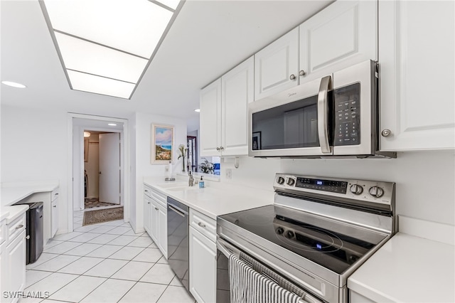 kitchen with light countertops, appliances with stainless steel finishes, light tile patterned floors, and white cabinetry
