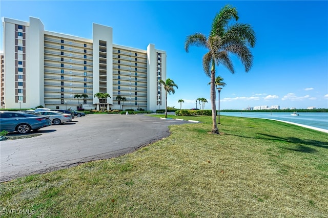 view of building exterior with uncovered parking and a water view