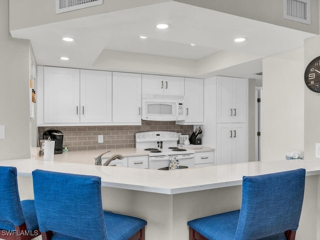 900 Collier Ct Unit 106, Marco Island, FL 34145 - kitchen with visible vents, decorative backsplash, a breakfast bar, and white appliances