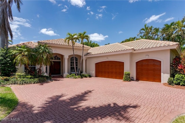 2363 Crayton Rd, Naples, FL 34103 - mediterranean / spanish house with a garage, stucco siding, decorative driveway, and a tiled roof