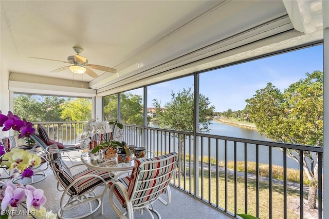 sunroom / solarium featuring a water view and ceiling fan