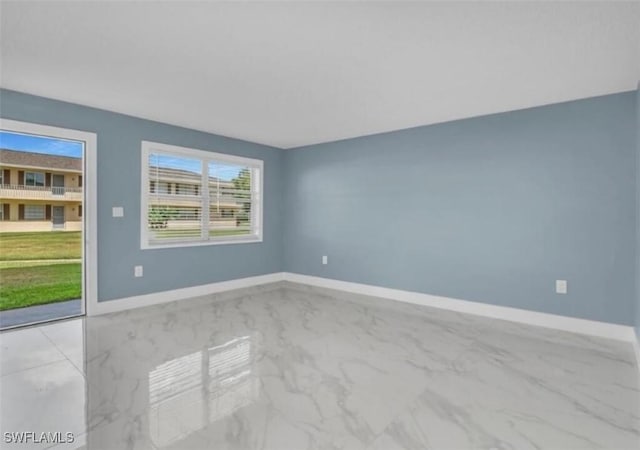 unfurnished room featuring marble finish floor and baseboards