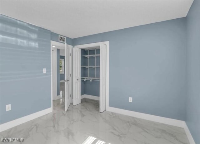 unfurnished bedroom with a closet, visible vents, marble finish floor, and baseboards