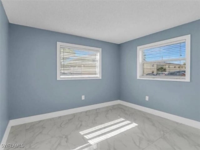 spare room with baseboards and marble finish floor
