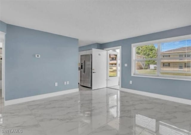unfurnished living room with baseboards and marble finish floor
