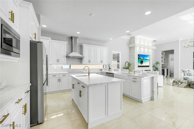 2927 Cinnamon Bay Cir, Naples, FL 34119 - kitchen with wall chimney range hood, appliances with stainless steel finishes, an island with sink, a sink, and white cabinets