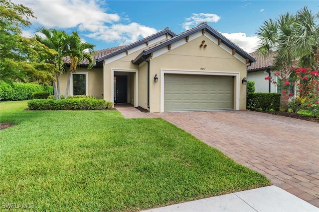 ranch-style home featuring decorative driveway, an attached garage, a front lawn, and stucco siding