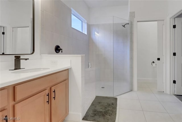 full bath featuring tile patterned flooring, a tile shower, and vanity