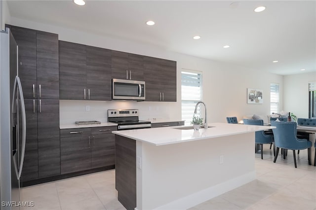 kitchen with light tile patterned floors, open floor plan, a sink, and stainless steel appliances
