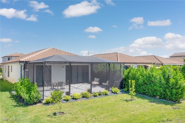 rear view of property featuring a patio, a yard, and a tiled roof