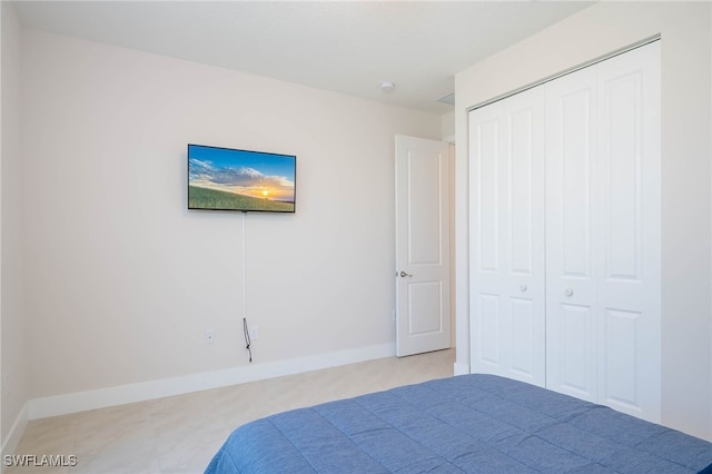 bedroom with light colored carpet, a closet, and baseboards