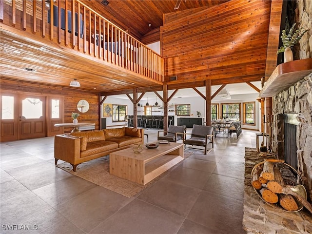 living room featuring a stone fireplace, a high ceiling, wood ceiling, and plenty of natural light