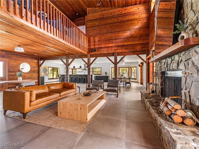living room with high vaulted ceiling, wood walls, finished concrete floors, and a wealth of natural light