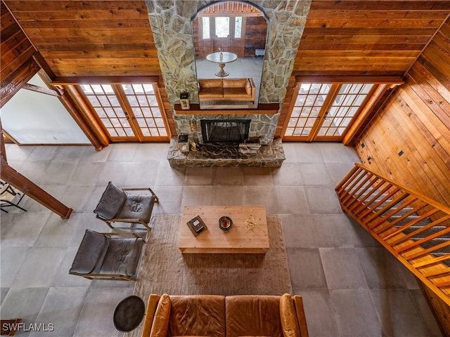 unfurnished living room with wooden walls, a stone fireplace, and wooden ceiling