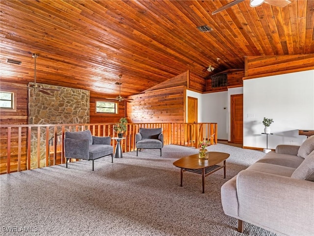 carpeted living area with visible vents, a ceiling fan, and wood walls