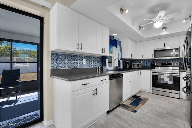 1210 Marlow St, Port Charlotte, FL 33952 - kitchen with dark countertops, a sink, white cabinetry, a raised ceiling, and appliances with stainless steel finishes