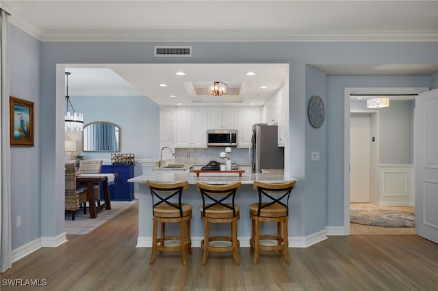 4761 W Bay Blvd Unit 303, Estero, FL 33928 - kitchen with stainless steel appliances, wood finished floors, a sink, a peninsula, and a chandelier