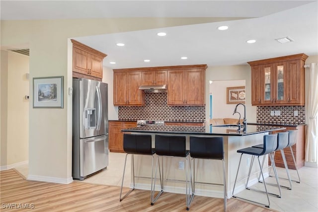 212 SE 30th Ter, Cape Coral, FL 33904 - kitchen featuring stainless steel refrigerator with ice dispenser, a sink, dark countertops, a kitchen bar, and under cabinet range hood