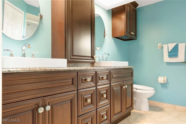 212 SE 30th Ter, Cape Coral, FL 33904 - bathroom featuring toilet, double vanity, tile patterned floors, and baseboards
