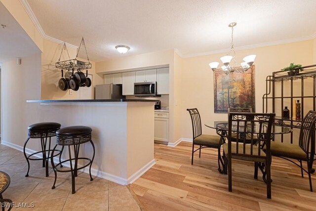 8617 River Homes Ln Unit 3108, Bonita Springs, FL 34135 - kitchen featuring appliances with stainless steel finishes, a chandelier, crown molding, white cabinetry, and a breakfast bar area