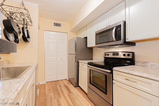 8617 River Homes Ln Unit 3108, Bonita Springs, FL 34135 - kitchen with appliances with stainless steel finishes, light wood-type flooring, a textured ceiling, a sink, and white cabinets