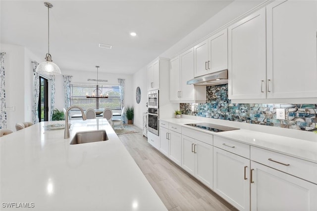 14071 Binghampton Dr, Fort Myers, FL 33905 - kitchen with black electric cooktop, stainless steel oven, white cabinets, light countertops, and under cabinet range hood