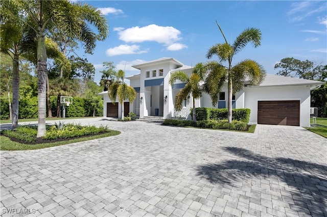 modern home featuring a garage, stucco siding, and decorative driveway