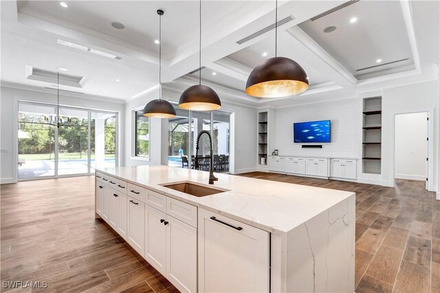 kitchen with coffered ceiling, visible vents, a sink, light stone countertops, and white cabinetry