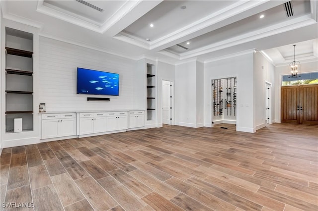 unfurnished living room with an inviting chandelier, light wood finished floors, baseboards, ornamental molding, and beam ceiling